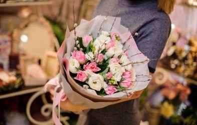 Woman holding a beautiful bouquet of tender flowers consisting of pink tulips and white ranunculus